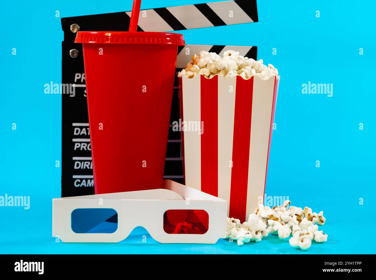 Bild der Filmklappertafel hinter rotem Soda-Glas, Eimer mit Popcorn und 3D-Brille auf blauem Hintergrund, Kino-Entertainment-Konzept Stockfoto