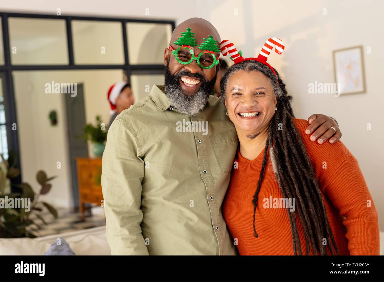 Glückliches multirassisches Paar, das festliche Accessoires trägt und zu Weihnachten zusammen lächelt Stockfoto