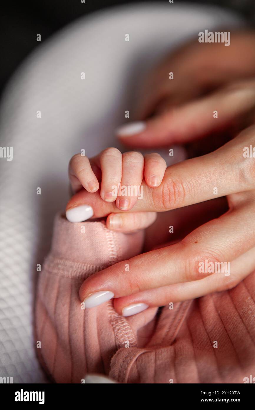 Nahaufnahme der Hand des Neugeborenen, die den Mutterfinger zärtlich greift, herzerwärmender Moment der Verbindung und Liebe zwischen Mutter und Kind Stockfoto