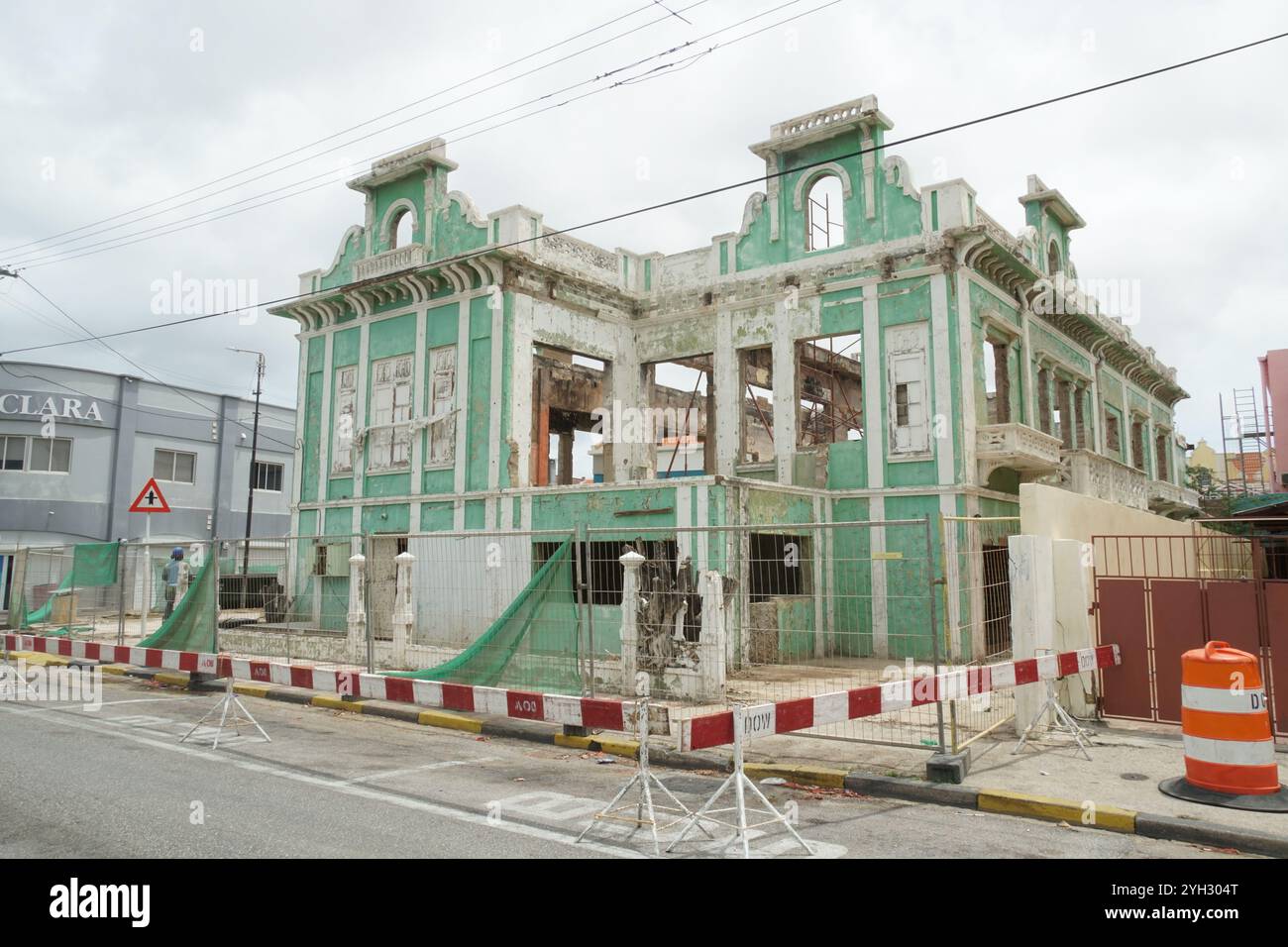 Ruiniertes grünes Gebäude in der Nähe der Innenstadt im Kolonialstil, das an der Straße in Oranjestad auf Aruba renoviert wird. Stockfoto