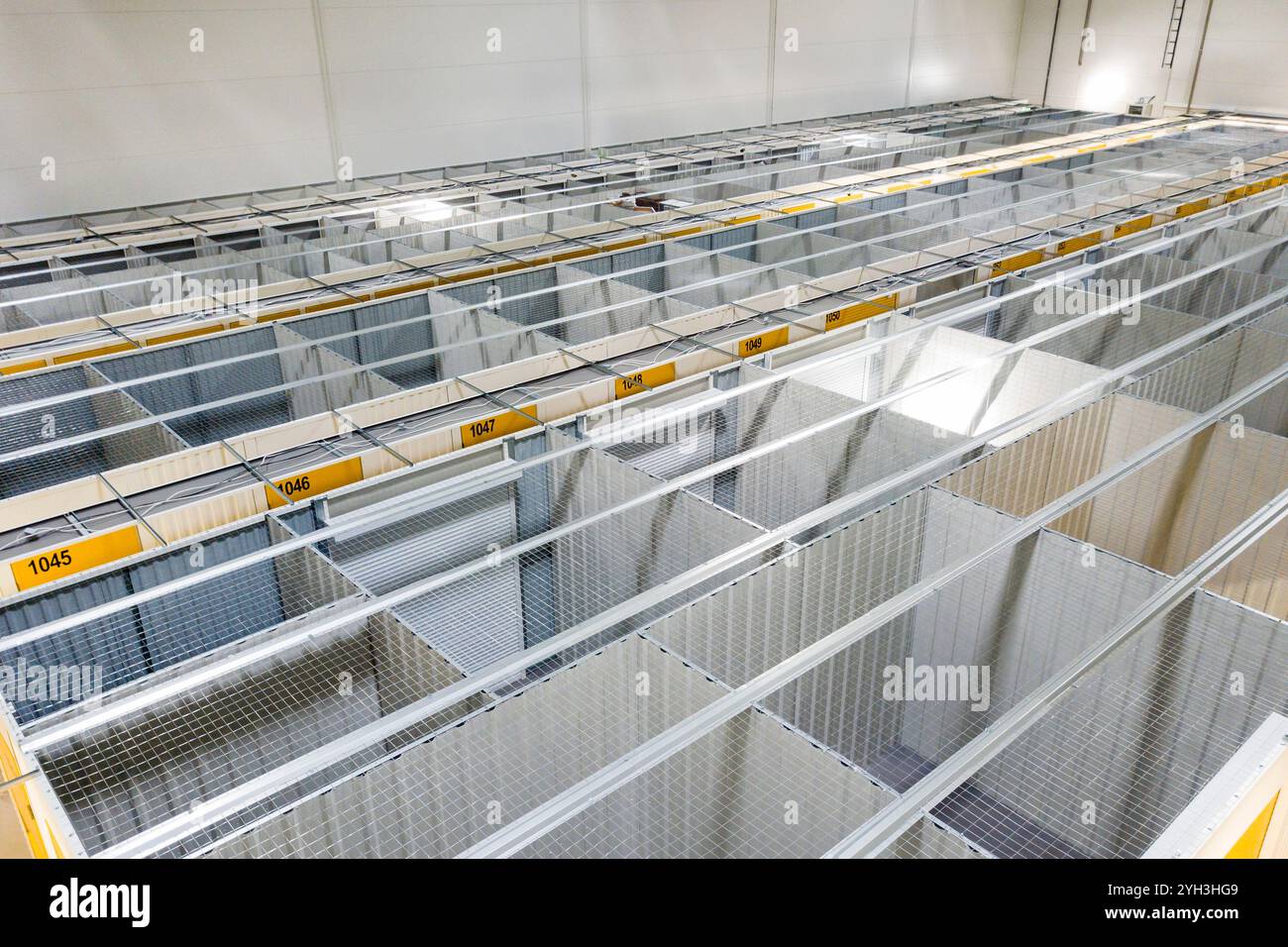 Ansicht von oben auf organisierte Metalllagereinheiten mit Gitterwänden und gelben Markierungen in einem Werk. Stockfoto