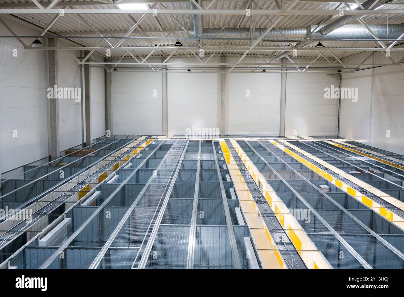 Ansicht von oben auf organisierte Metalllagereinheiten mit Gitterwänden und gelben Markierungen in einem Werk. Stockfoto