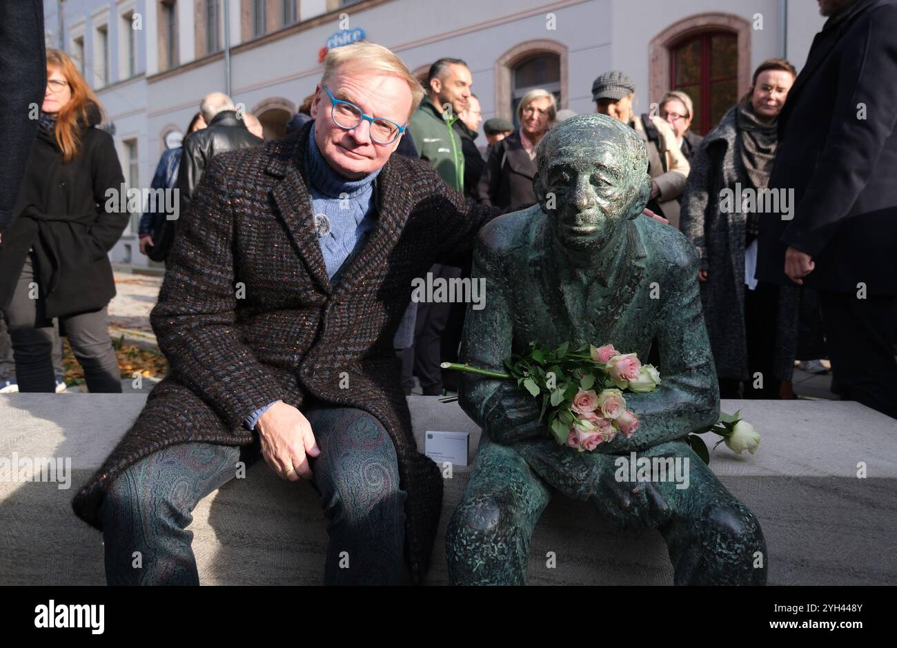 Chemnitz, Deutschland. November 2024. Uwe Steimle, Schauspieler und Kabarettist, sitzt neben der Bronzeskulptur „Bank für Justin Sonder“ am Brühl. Justin Sonder, geboren 1925, erlebte die Pogromnacht am 9. November 1938 in Chemnitz und wurde 1943 nach Auschwitz deportiert. Er überlebte und kehrte 1945 in seine Heimatstadt zurück. Er kämpfte bis zu seinem Tod 2020 gegen den Antisemitismus. Am Samstag (09.11.2024) wurde auf Initiative einer breiten Allianz zu seiner Erinnerung ein Bronzeporträt von ihm enthüllt. Quelle: Sebastian Willnow/dpa/Alamy Live News Stockfoto