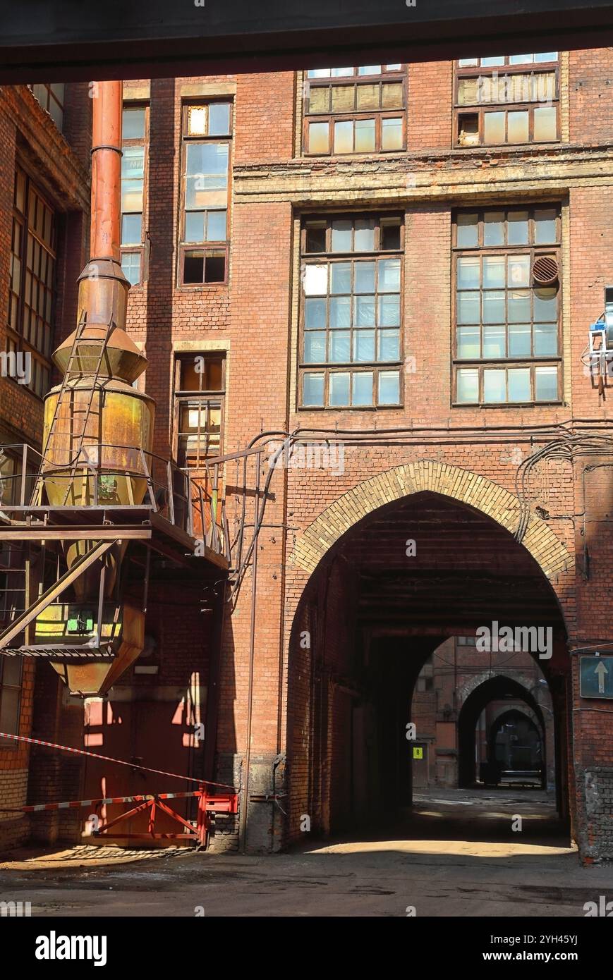 Blick auf den alten Industriehof mit roten Ziegelfassaden und Röhren Stockfoto