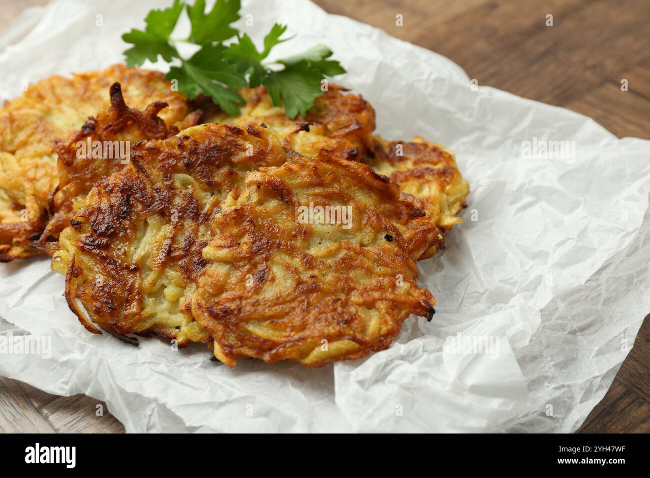 Leckere Kartoffelpfannkuchen und Petersilie auf Holztisch, Nahaufnahme Stockfoto