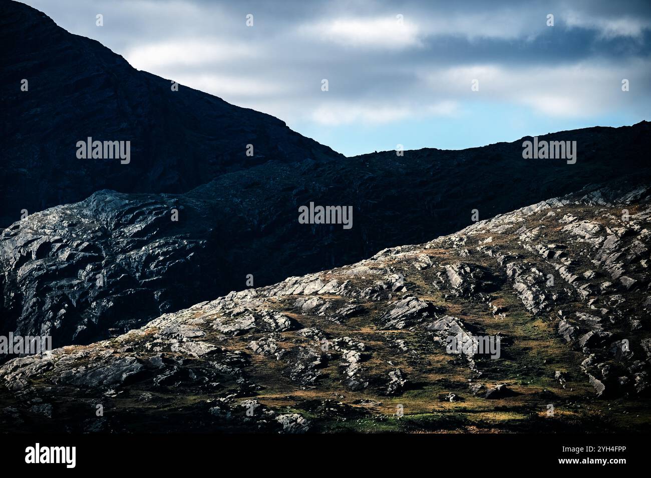 Ein atemberaubender Blick auf zerklüftete Berghänge mit einzigartigen Felsformationen unter einem leicht bewölkten Himmel. Die Landschaft fängt das Wesen der Unte ein Stockfoto