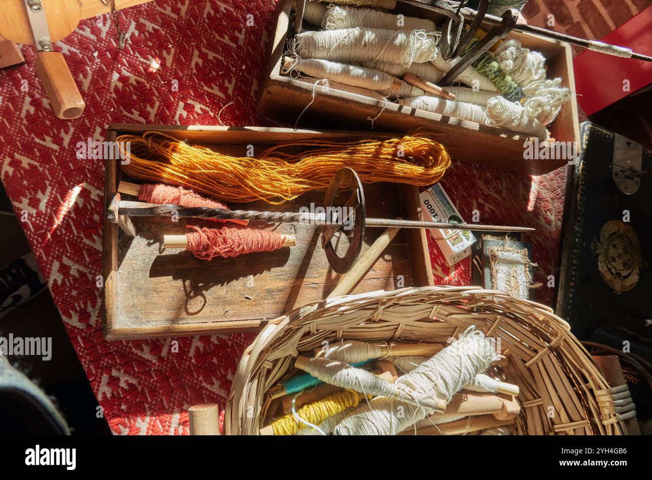 Trevi, Italien - 11 02 2024 - handwerkliche Webzubehör in rustikalem Studio mit bunten Garnspulen Holzwerkzeugen und Korb aus Weide, beleuchtet von Natural Stockfoto