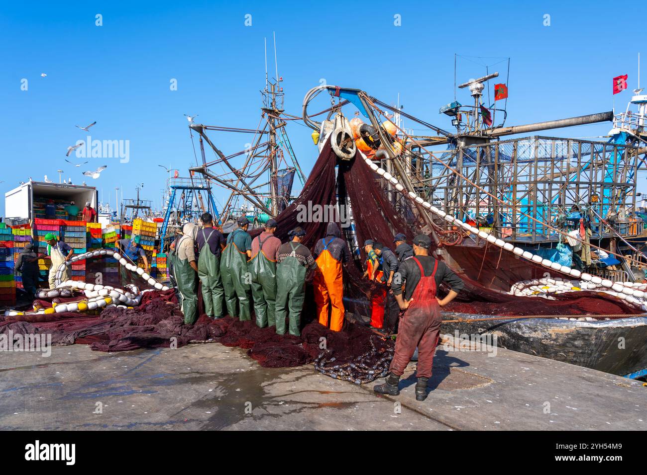 Fischer, die Fischernetze von einem Fischerboot im Hafen ziehen. Essaouira, Marokko, Afrika Stockfoto