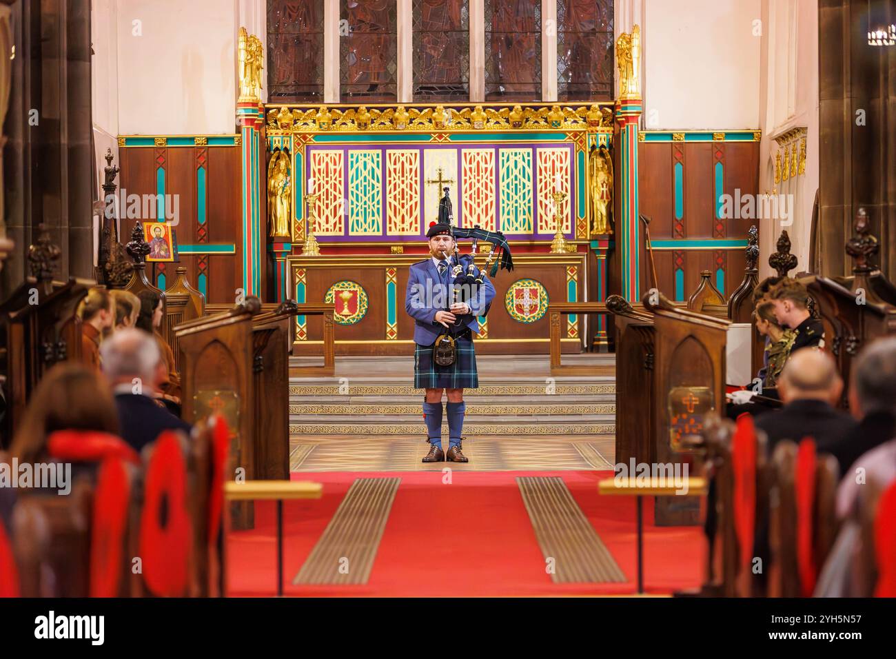 Warrington, Cheshire, England, Großbritannien. November 2024. Das jährliche Festival of Remembrance findet in der St. Elphin's Parish Church statt. Es war ein Abend, um an den Dienst und die Opfer unserer Streitkräfte in weltweiten Konflikten zu erinnern und zu ehren. Ein einsamer Piper spielt die Soldiers Lament, Flowers of the Forest vor der Kirche. Quelle: John Hopkins/Alamy Live News Stockfoto