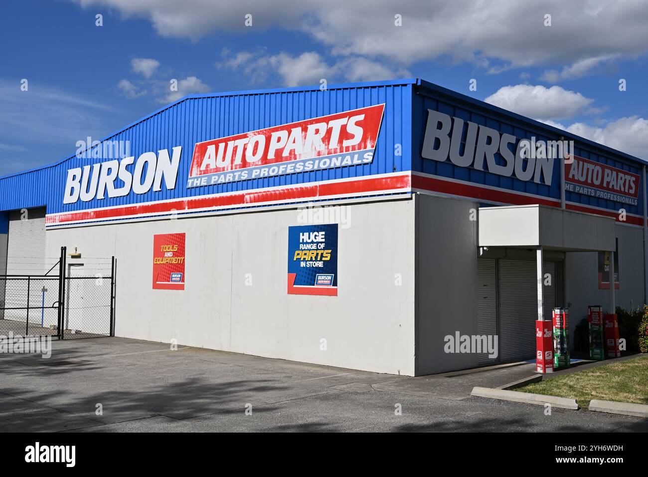 Sonnendurchflutetes Äußere eines Burson Auto Parts Stores mit weiß-, Blau- und Rot-Branding, das an einem sonnigen Tag an der Seite des Gebäudes hell beleuchtet wird Stockfoto