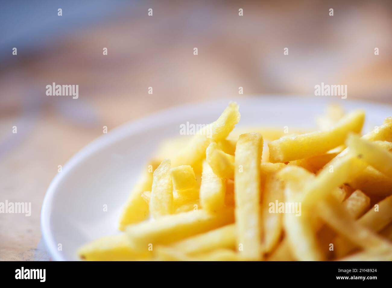 Ein herrlicher und knuspriger Haufen goldenbrauner Pommes frites ist wunderschön auf einem makellos weißen Teller angeordnet, der zum Genießen bereit ist Stockfoto