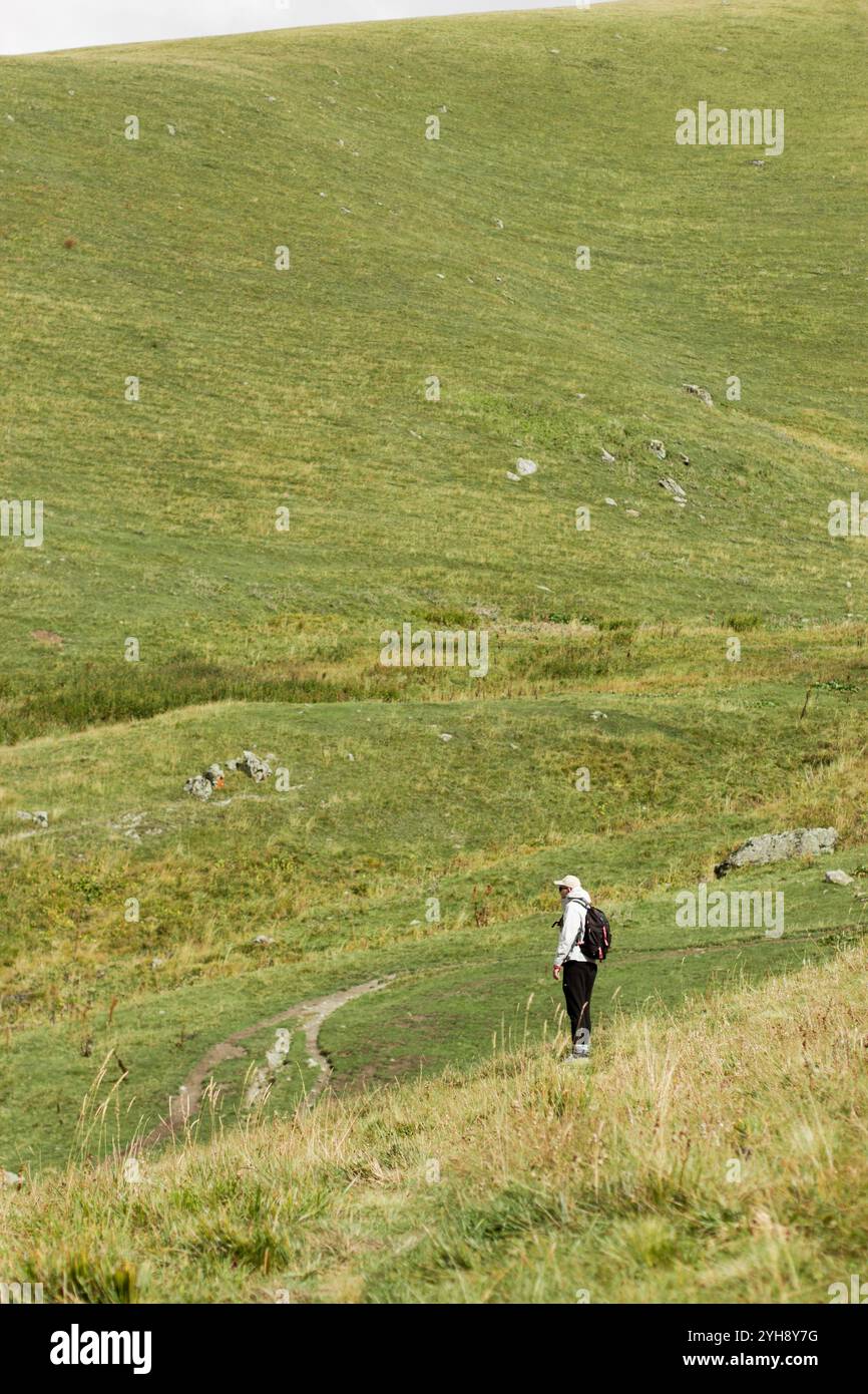 Dieses vertikal ausgerichtete Foto zeigt einen einsamen Wanderer in der herbstlichen Landschaft Georgiens. Die Person, die in Outdoor-Ausrüstung mit einem Rücken gekleidet ist Stockfoto