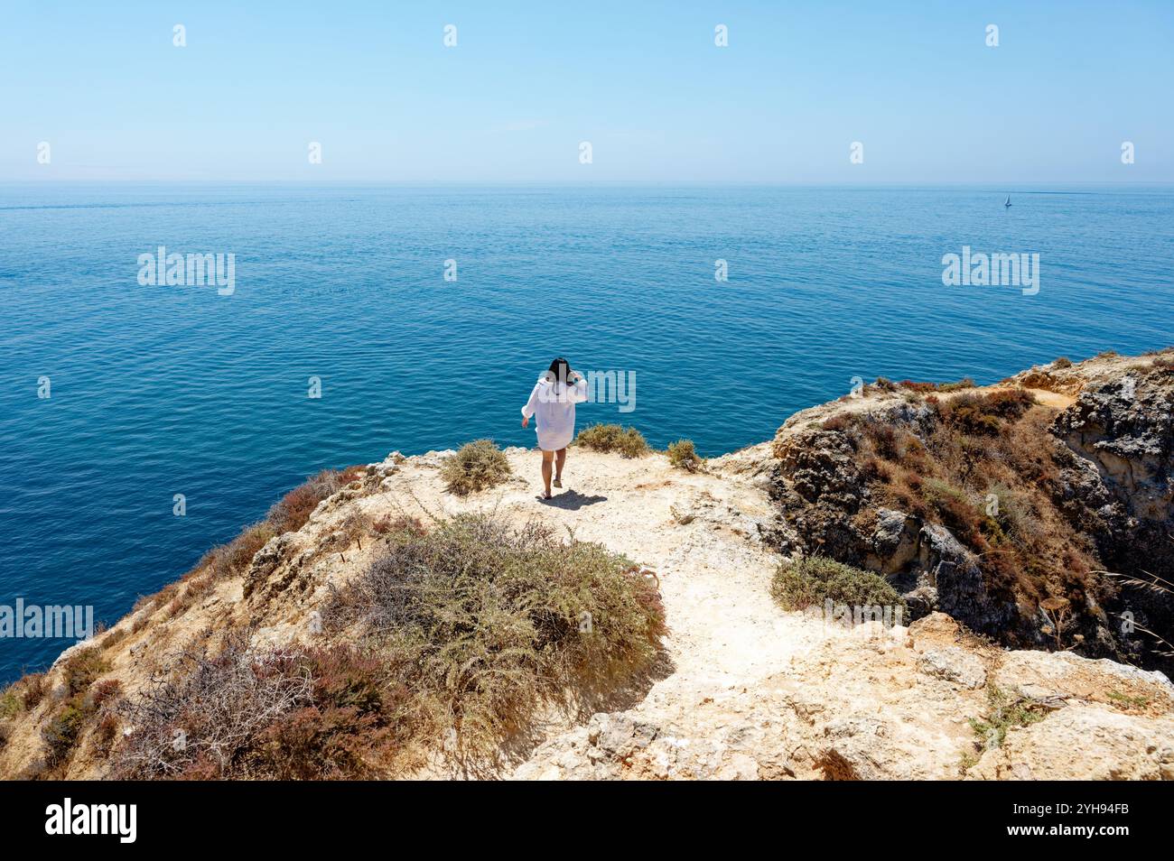Die junge Frau steht auf einer Klippe mit Blick auf das weite Meer bei Ponta da Piedade in Lagos Stockfoto