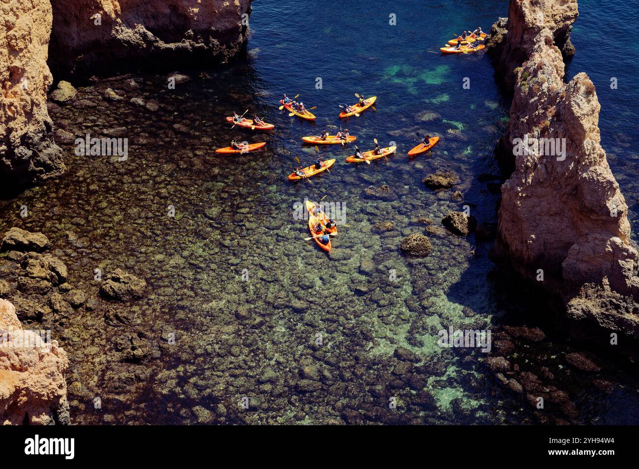 Eine Gruppe von Kajakfahrern paddelt durch klares Wasser rund um die Felsformationen von Ponta da Piedade Stockfoto