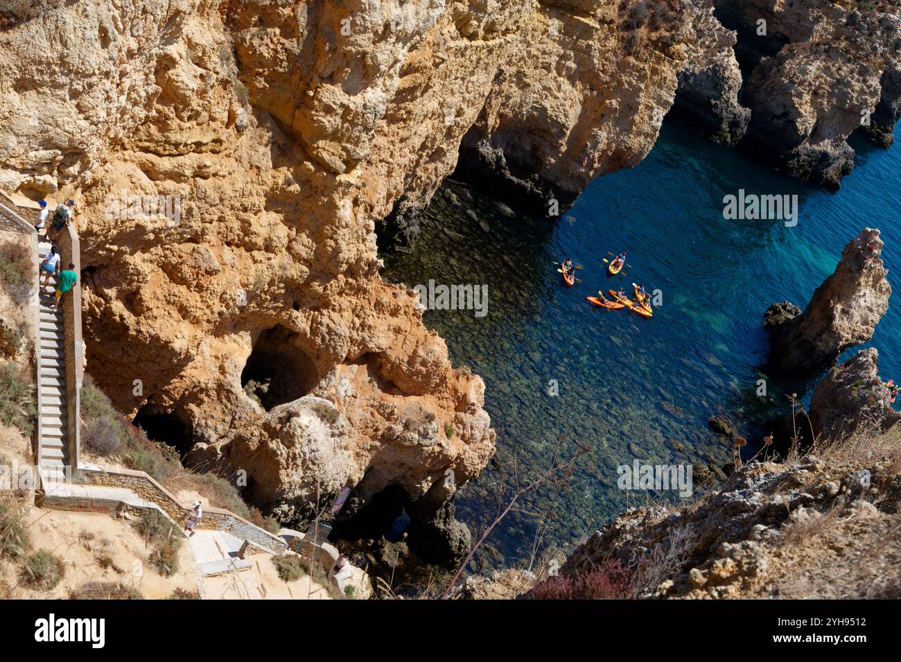 Kajakfahrer erkunden das türkisfarbene Wasser unter den dramatischen Klippen und der zerklüfteten Treppe bei Ponta da Piedade Stockfoto