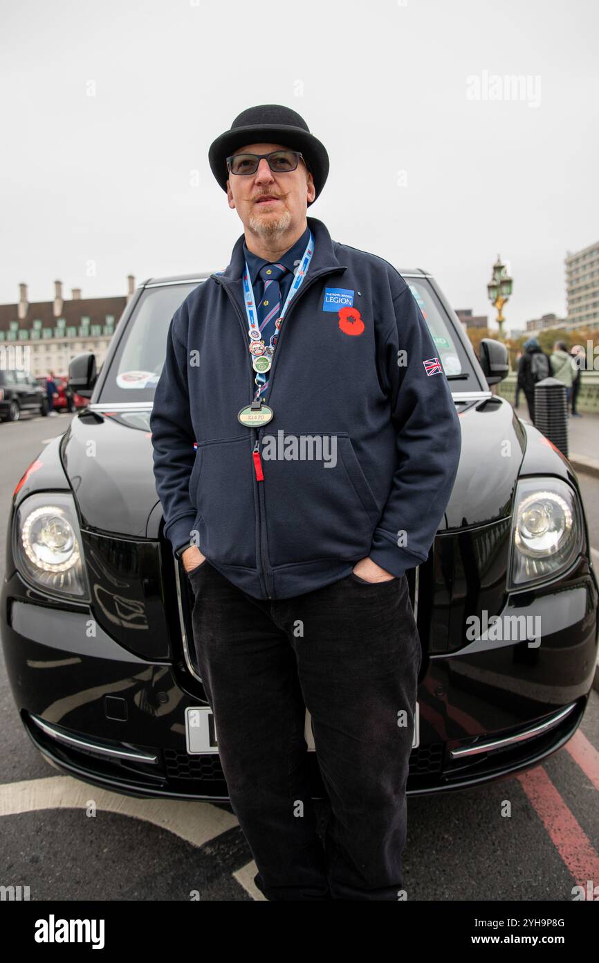 Ein Londoner Taxifahrer steht vor seinem Taxi. Poppy Cabs wurde vor 15 Jahren von Londoner Taxifahrern gegründet und bietet Militärveteranen kostenlose Fahrten an, die am jährlichen Gedenktag-Service im Cenotaph in Westminster, London, teilnehmen. Inspiriert vom Poppy Appeal der Royal British Legion, wo rote Mohnabzeichen gegen Spenden ausgetauscht werden, organisieren sich diese engagierten Taxifahrer im Rahmen der „Poppy Cabs“-Initiative. Jedes Jahr bieten Fahrer kostenlose Fahrten zu Veteranen von den großen Bahnhöfen in ganz London an, um sicherzustellen, dass sie sicher und pünktlich zu den Gedenkfeiern ankommen Stockfoto