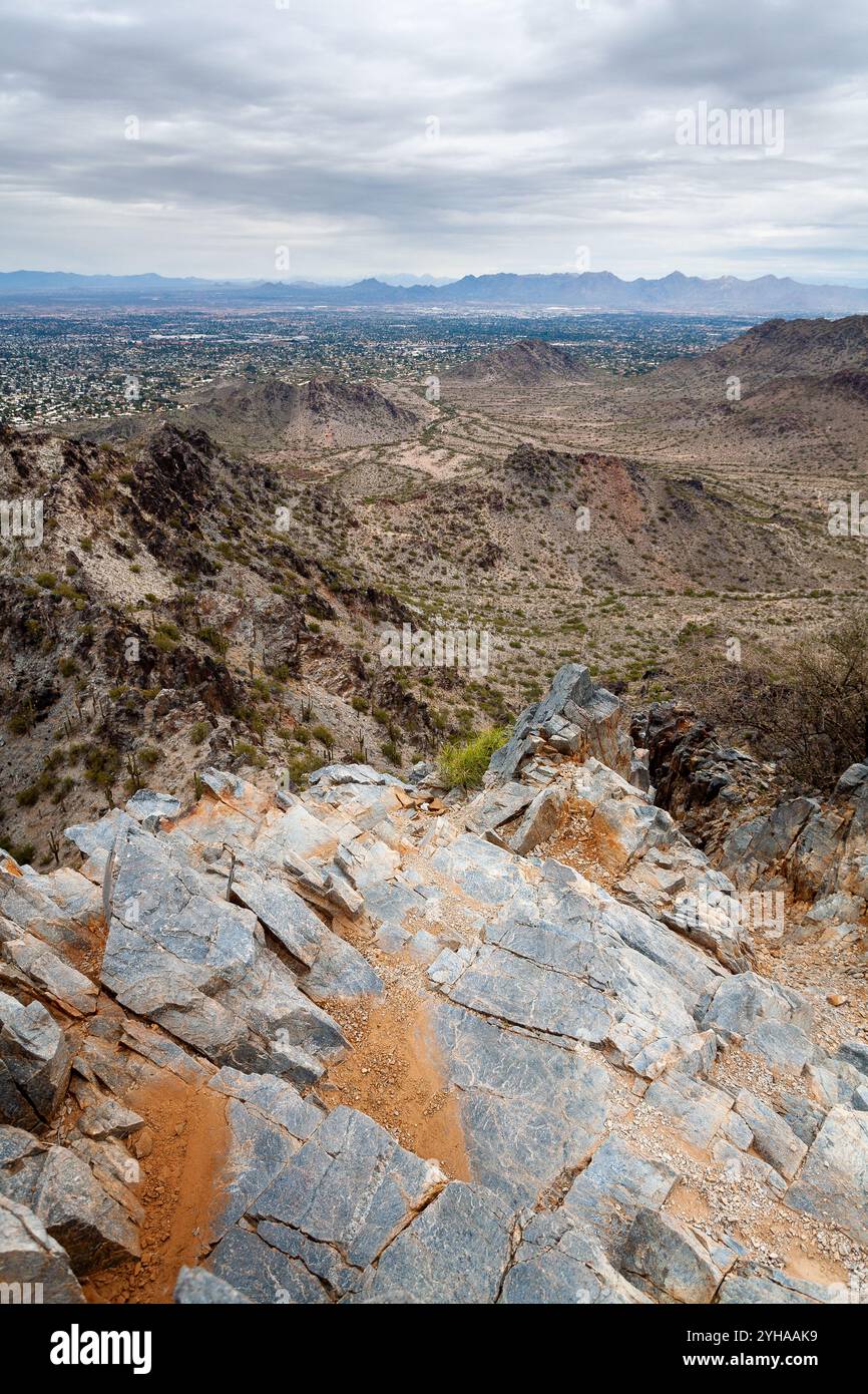 Der felsige Gipfel des Piestawa Peak erstreckt sich in Richtung der Stadt Phoenix unter bewölktem Himmel. Phoenix Mountains Preserve, Arizona Stockfoto