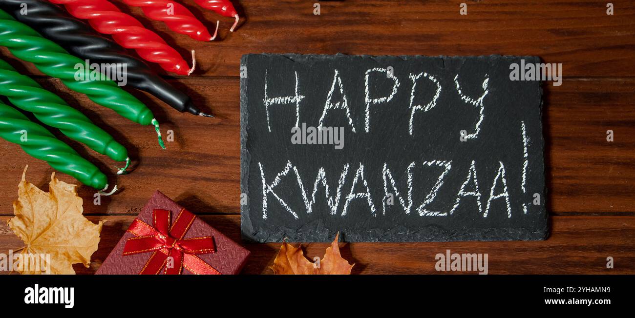 Kwanzaa afroamerikanischer Feiertag. Sieben Kerzen rot, schwarz und grün auf einem natürlichen Holzhintergrund. Symbole des afrikanischen Erbes. Gratulations-Ansinn Stockfoto