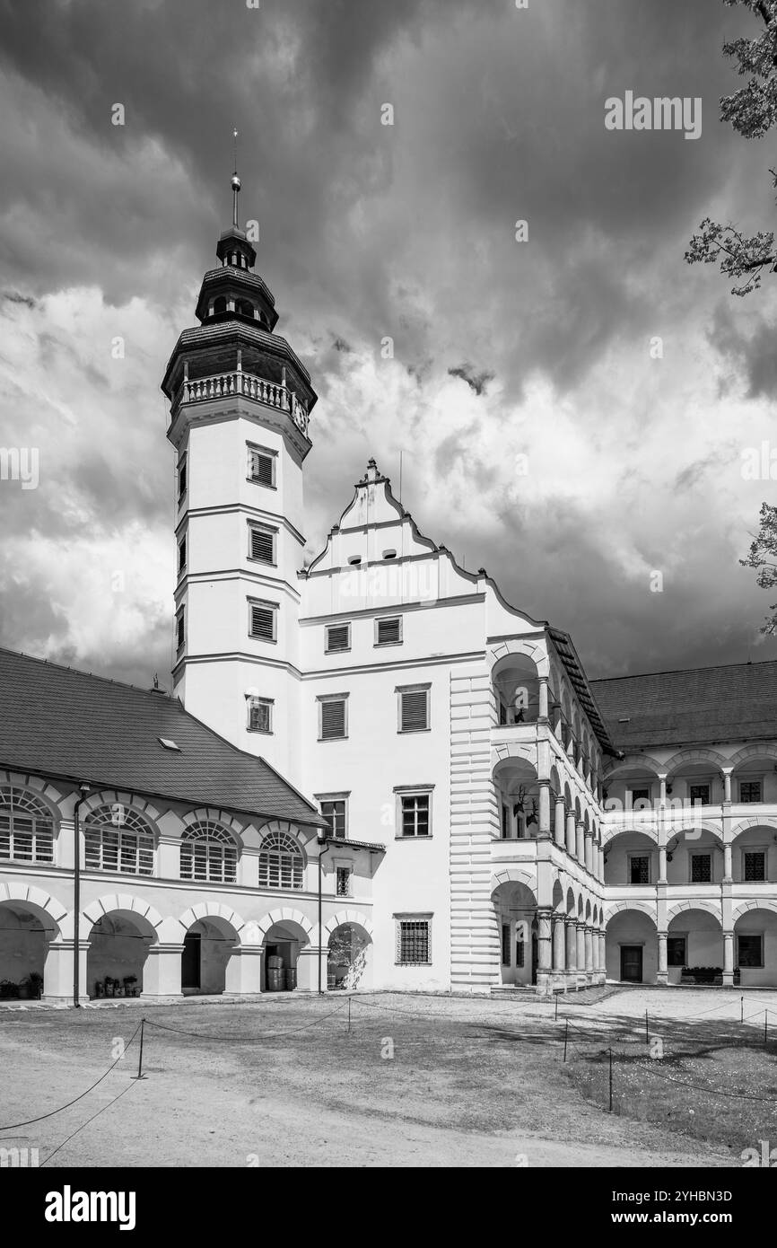 Der Innenhof des Velke Losiny Chateau zeigt elegante Architektur vor dem Hintergrund dunkler, bedrohlicher Wolken, die einen eindrucksvollen Kontrast bilden. Schwarzweiß-Fotografie. Stockfoto