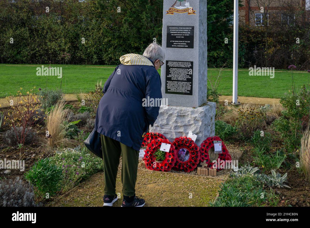Ältere Frau, die Mohnkränze ansieht, die für den Gedenktag gelegt wurden, im Simpson Manor Memorial Garden, Wootton, Northampton, Großbritannien Stockfoto
