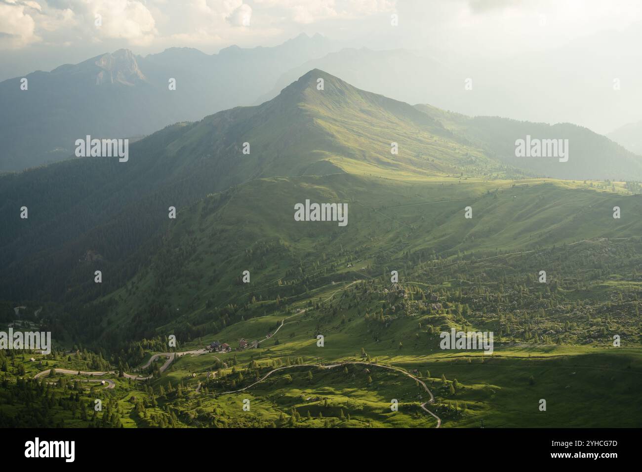 Summer view from Monte Nuvolau, showcasing rolling green hills and mountain peaks in the Dolomites. The sunlight gently illuminates the landscape Stockfoto