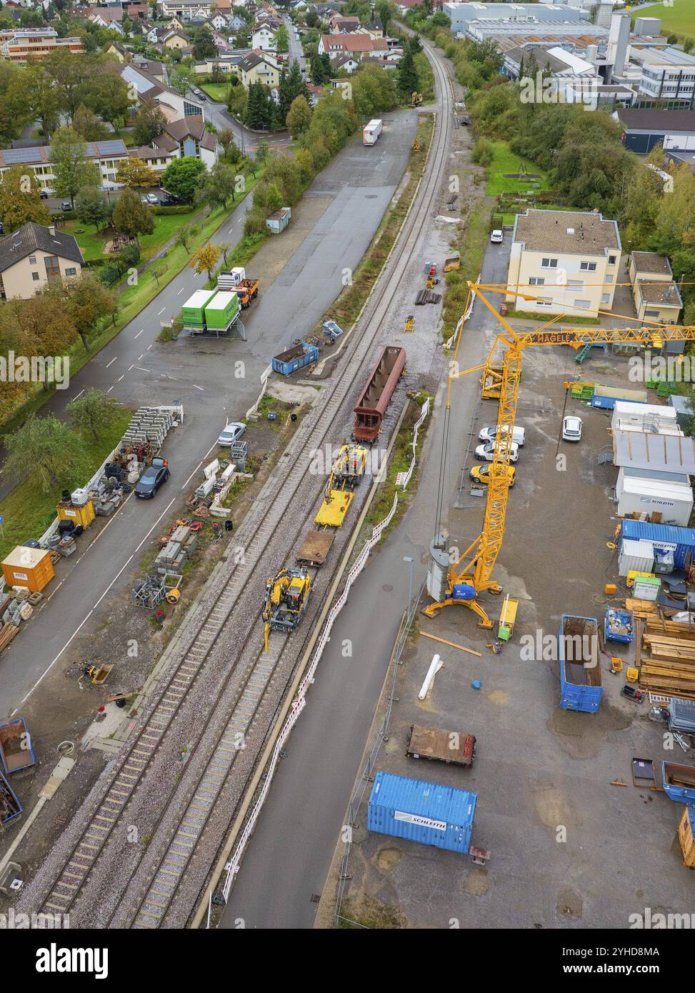 Eine Baustelle neben Bahngleisen und eine Straße mit mehreren Maschinen und einem großen gelben Kran, Stanzmaschine, Hermann Hessebahn, Althengstett Stockfoto