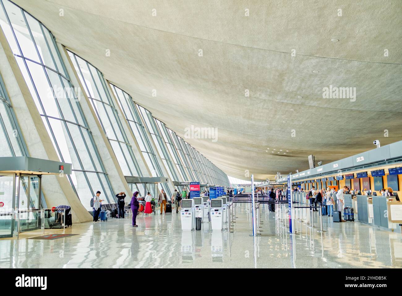 Dulles International Airport Curved Dachdesign Dulles Virginia // DULLES, Virginia — die obere Halle des Washington Dulles International Airport zeigt Eero Saarinen's ikonisches geschwungenes Dach Design, eines der bekanntesten Beispiele für moderne Flughafenarchitektur aus der Mitte des Jahrhunderts. Die markante Dachkonstruktion des Terminals, die 1962 fertiggestellt wurde, schafft einen dramatischen, weitläufigen Innenraum, der zu einem Markenzeichen des Flughafens geworden ist. Betonsäulen stützen das geschwungene Dach und veranschaulichen Saarinen's innovative strukturelle Herangehensweise, die Form und Funktion in Einklang bringt. Die Finnisch-Amer Stockfoto