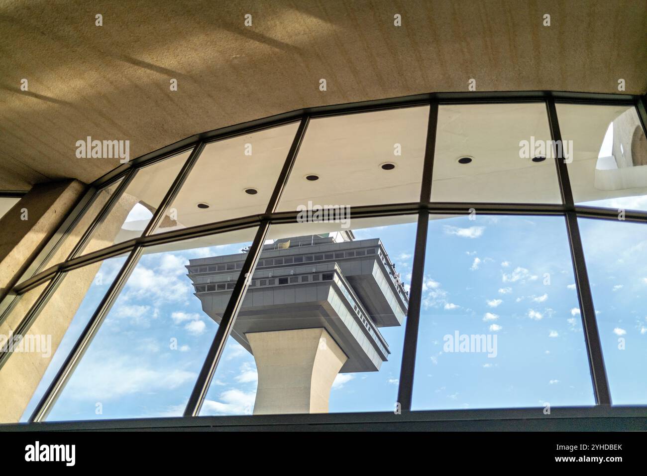 Air Traffic Control Tower Dulles International Airport Virginia // DULLES, Virginia — der Air Traffic Control Tower am Washington Dulles International Airport ist durch die Glasfenster des Terminals zu sehen. Das Hauptterminal des Flughafens, das vom modernistischen Architekten Eero Saarinen entworfen und 1962 fertiggestellt wurde, verfügt über eine markante Dachkonstruktion, die zu einem architektonischen Wahrzeichen geworden ist. Dulles ist das wichtigste internationale Tor zur Region Washington DC und bietet jährlich Millionen von internationalen und inländischen Passagieren an. Die Anlage verbindet die National Capital Region Stockfoto