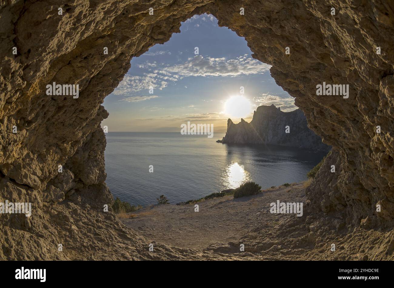 Blick von einer kleinen Grotte auf einen Abendsonnenuntergang hinter den Küstenklippen. Krim Stockfoto