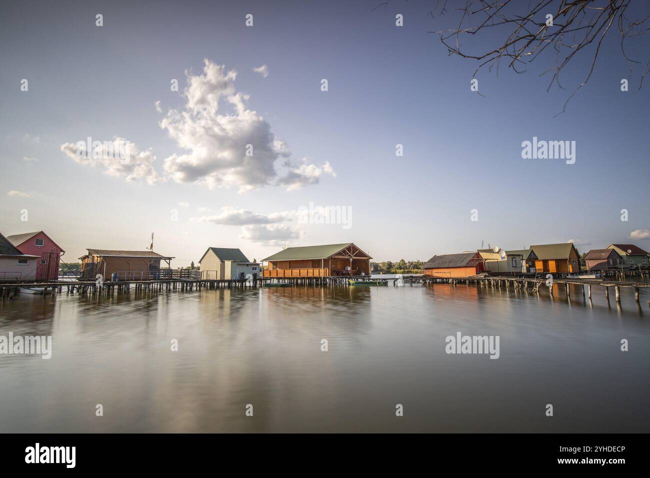 Holzhäuser im Wasser. Ferienort am See bei Sonnenuntergang. Lange Holzstege führen zu den einzelnen Häusern. Landschaftsaufnahme des schwimmenden V Stockfoto