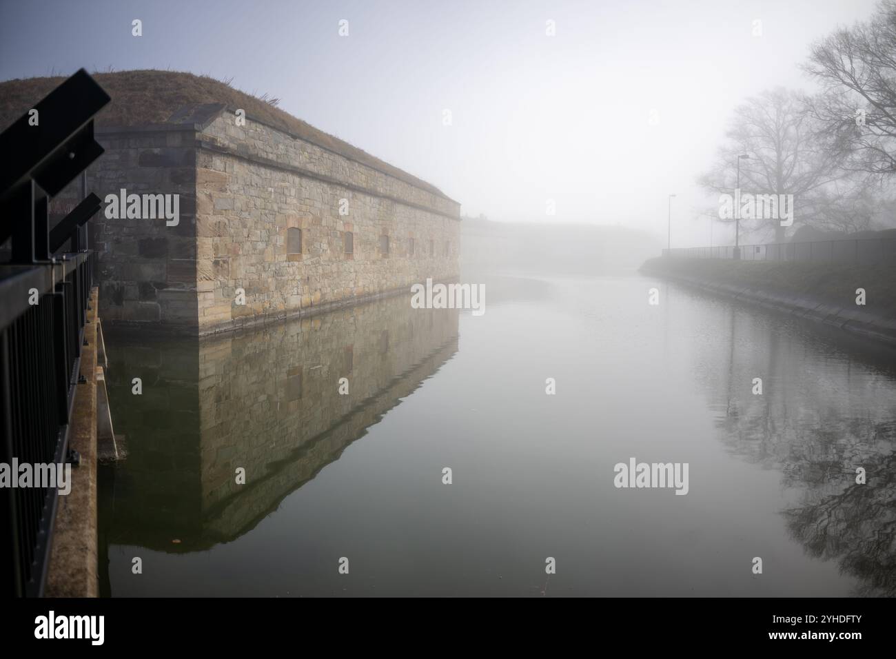 Fort Monroe Moat und Befestigungsanlagen Hampton Virginia // HAMPTON, Virginia — der historische Burggraben und die äußeren Befestigungen von Fort Monroe, Amerikas größtem Steinfort, tauchen durch den Morgennebel auf. Die atmosphärischen Bedingungen betonen die massiven Granitmauern und Verteidigungsmerkmale dieser Küstenbefestigung aus dem 19. Jahrhundert. Dieses erhaltene militärische Meisterwerk zeigt eine anspruchsvolle Küstenverteidigungsarchitektur. Stockfoto