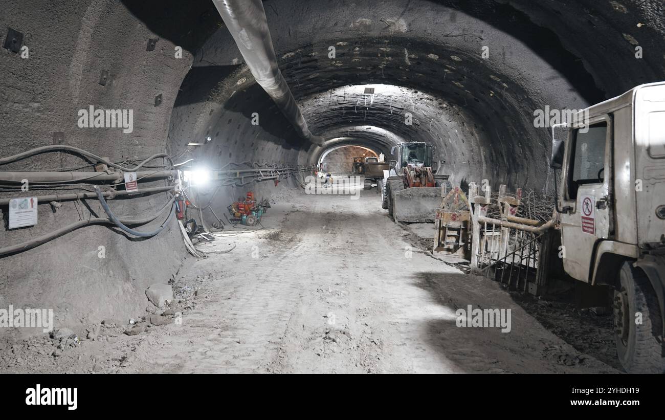 Eine Tunnelbaustelle mit LKW und Ausrüstung unter künstlicher Beleuchtung Stockfoto