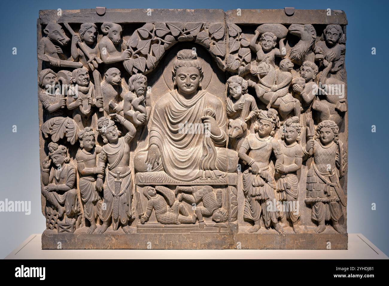 WASHINGTON DC, USA – Eine Schieferreliefplatte aus dem alten Gandhara zeigt Buddhas Erleuchtung und zeigt ihn in Meditation, während Maras Dämonenarmee versucht, seine Konzentration zu stören. Diese Platte wurde während der Kushan-Dynastie (Ende des 2. Bis Anfang des 3. Jahrhunderts n. Chr.) geschaffen und stellt den Buddha mit einer erdberührenden Geste (bhumisparsha mudra) dar, die seinen Triumph über Tod und Begehren symbolisiert. Die Szene stellt Buddhas heitere Symmetrie den verzerrten Formen von Maras Dämonen gegenüber. Stockfoto