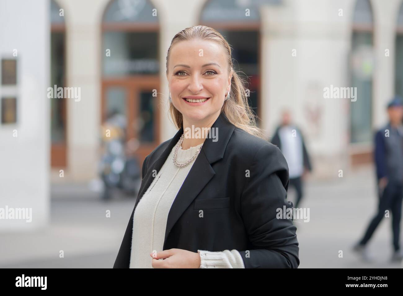 Porträt einer selbstbewussten Frau mittleren Alters mit europäischen Akzenten vor den verschwommenen Silhouetten einer großen Stadt. Stockfoto