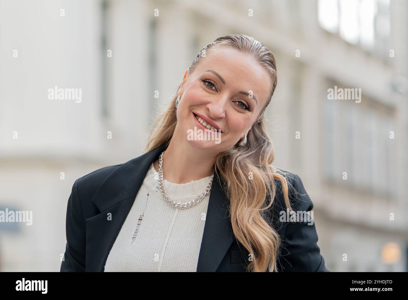 Porträt einer schönen 35-40-jährigen europäischen Frau vor dem Hintergrund verschwommener Silhouetten städtischer Architektur. Stockfoto