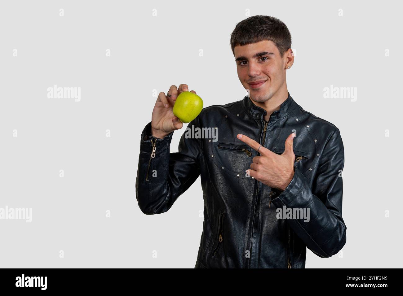 Stilvoller Mann zeigt und zeigt auf einen grünen Apfel, fördert gesunde Essgewohnheiten Stockfoto