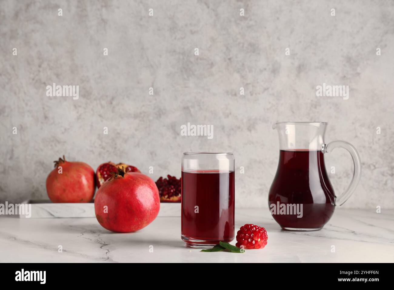 Glas und Kanne mit frischem Granatapfelsaft auf weißem Hintergrund Stockfoto