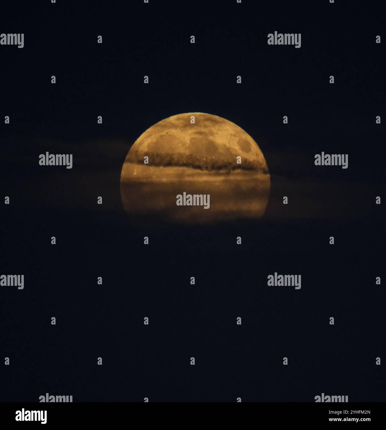 Der Mond, der tief am Horizont aufsteigt, mit Wolken darüber und erzeugt einen gruseligen Effekt mit Kopierraum. Stockfoto