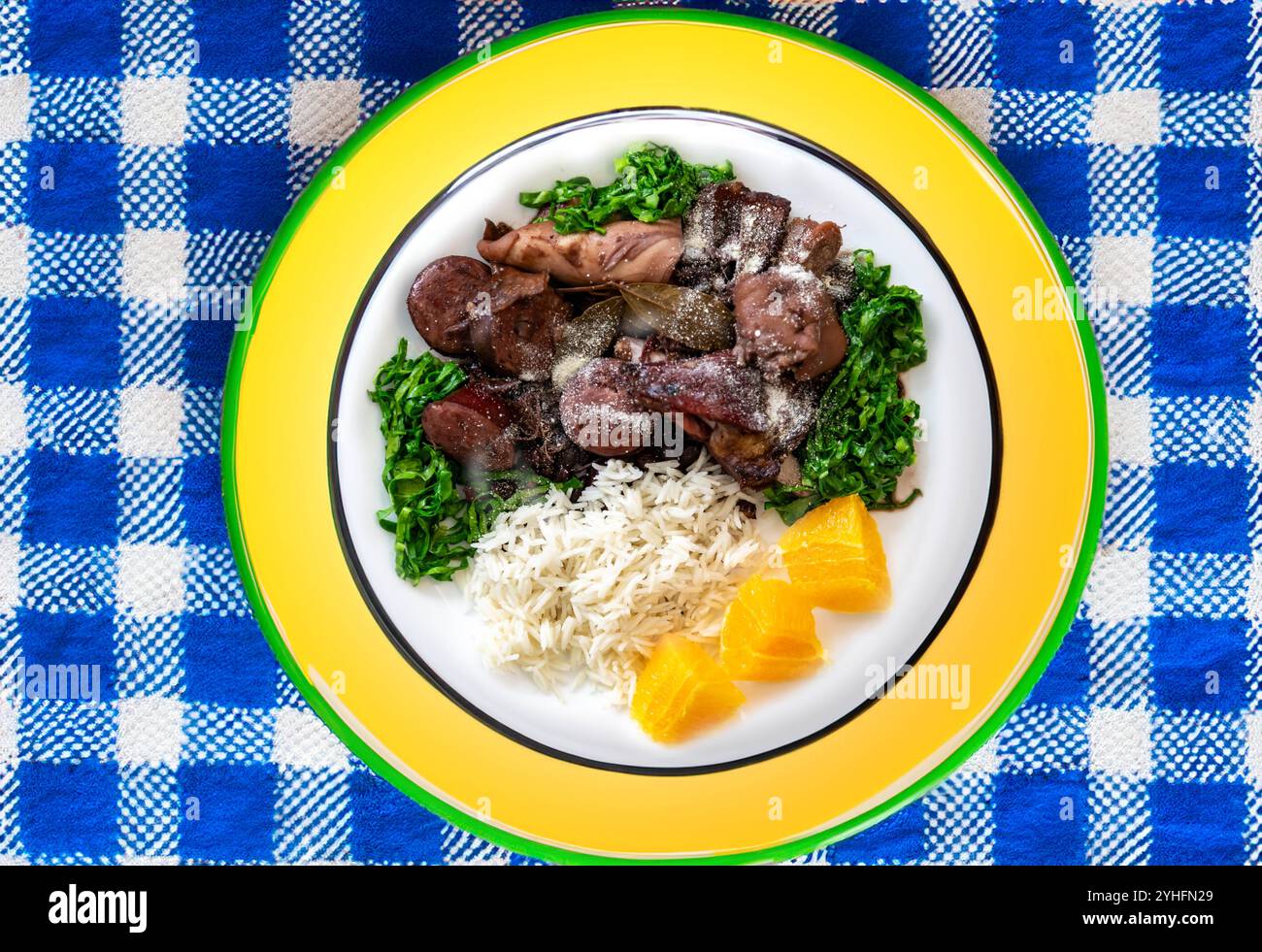 Die beste und traditionellste brasilianische Feijoada der Welt, serviert auf einem grünen und gelben Teller Stockfoto