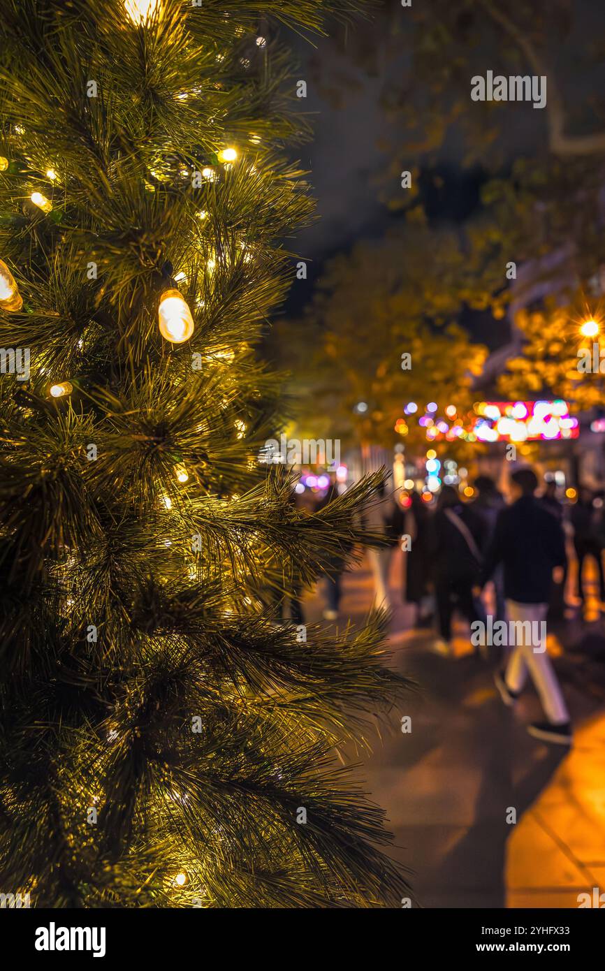 weihnachtsdekoration mit goldenen Lichtern und Farben auf der Straße mit Leuten, die auf der Straße einkaufen Stockfoto