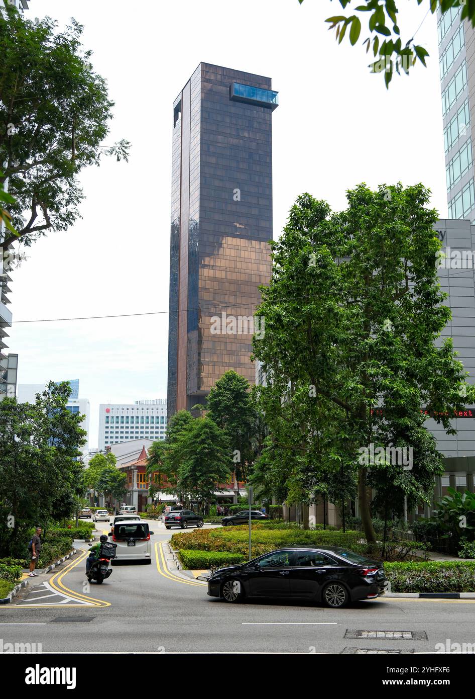 Der goldbraune Wolkenkratzer des Clan Hotel hebt sich vom Grün der Stadtlandschaft Singapurs ab. Stockfoto