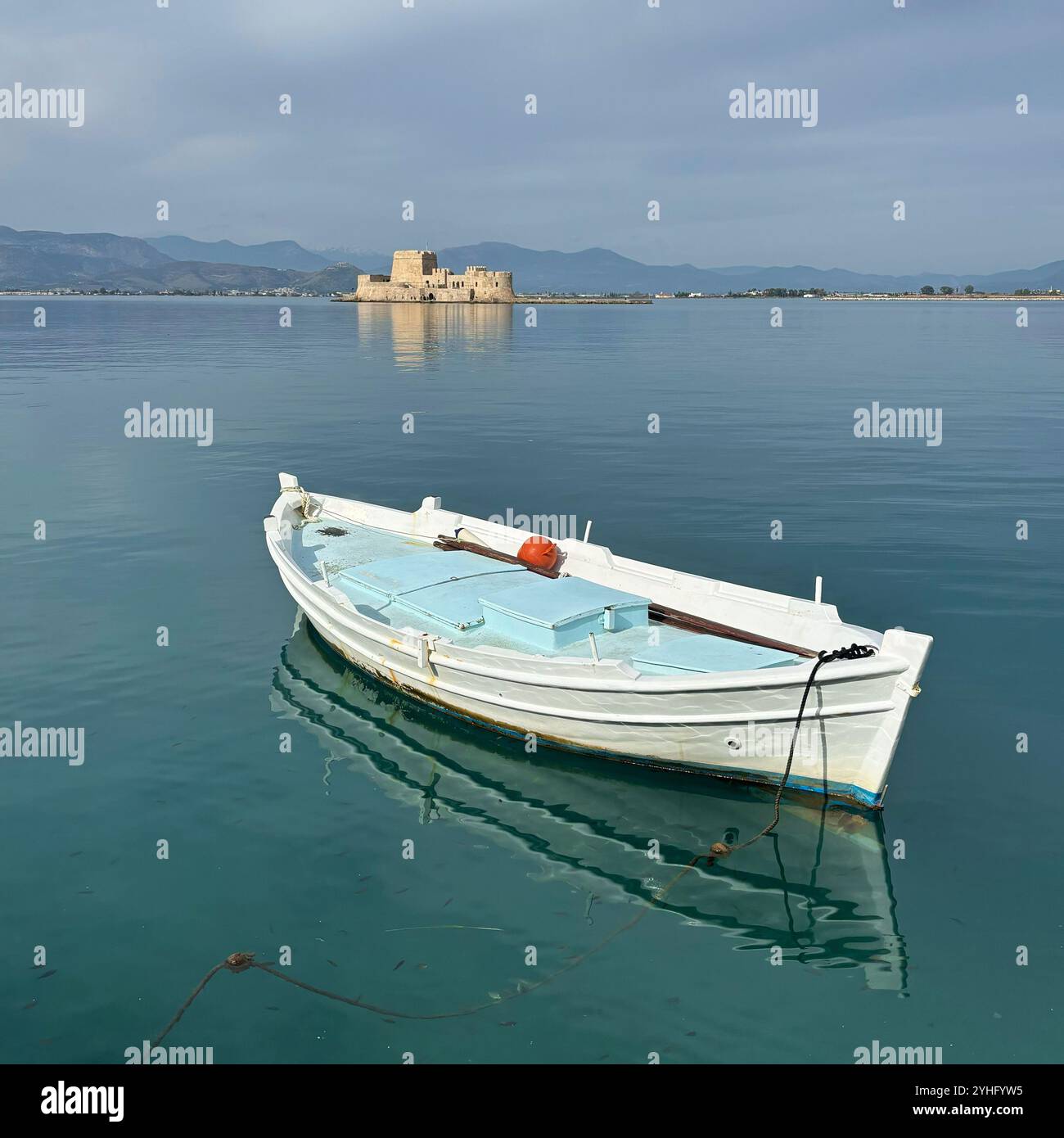 Ruhiger Blick auf ein einsames weißes Fischerboot, das auf ruhigen Gewässern in Nafplio, Griechenland, schwimmt. - Smartphone-aufgenommenes Stockfoto