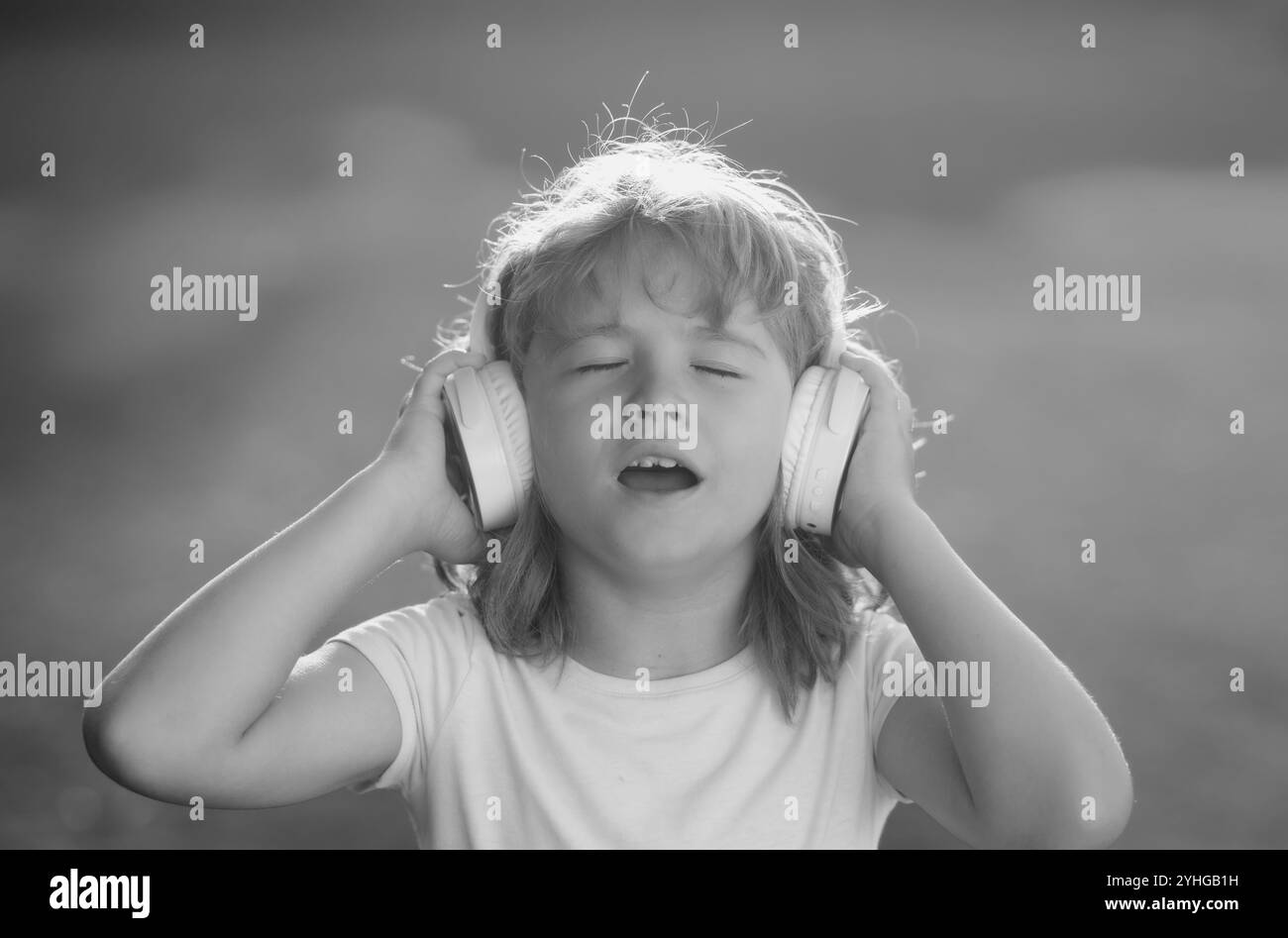 Singende Kinder. Kind, das Musik mit Kopfhörern hört, begeistert von offenem Mund. Lustiges Kindergesicht. Stockfoto