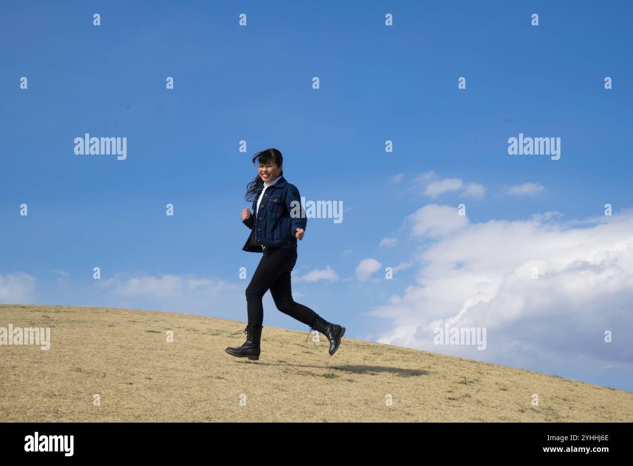 Frau, die unter blauem Himmel läuft Stockfoto
