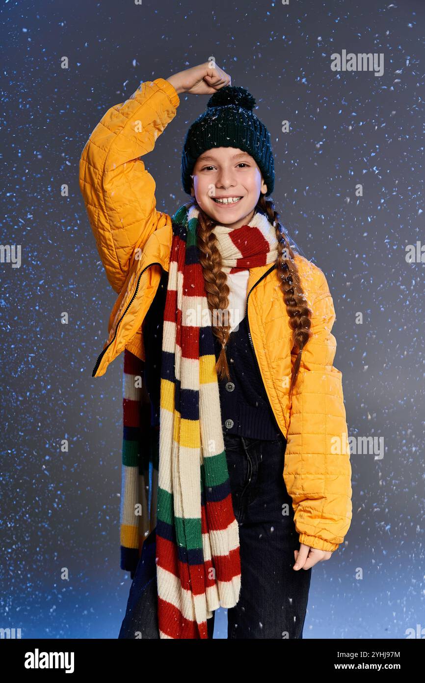 Ein fröhliches Mädchen in heller Winterkleidung genießt den magischen Schneefall mit Spannung. Stockfoto