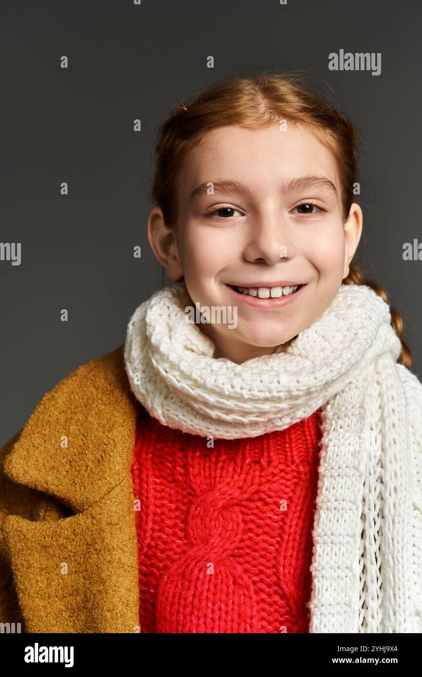 Ein junges Mädchen, das im Winter mit einem pulsierenden Pullover und einem warmen Schal verziert ist, strahlt fröhlich im Winter. Stockfoto