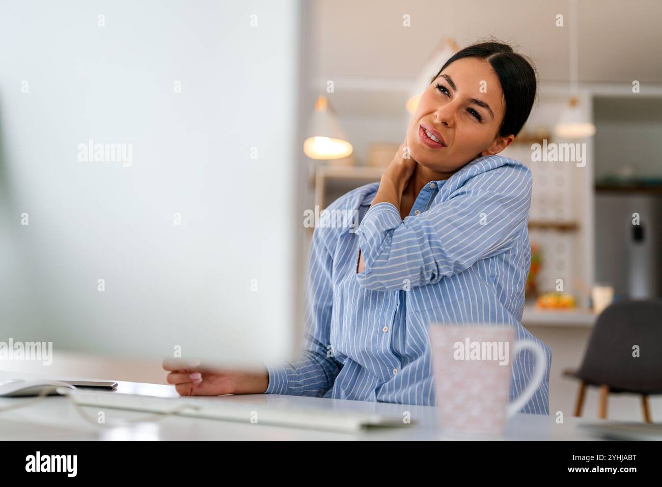 Müde Geschäftsfrau schläfrig und gelangweilt vom Sitzen am Schreibtisch für eine lange Zeit und hat ein Bürosyndrom Stockfoto