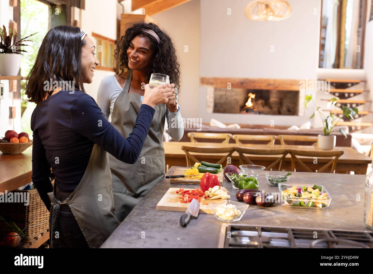 Zwei multirassische Freundinnen, die zu Hause Drinks trinken, während sie Thanksgiving-Mahlzeit zubereiten Stockfoto