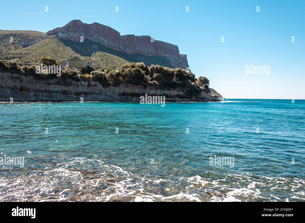 Côte d'Azur, Frankreich - 24. Juli 2010: Türkisfarbenes Wasser trifft auf zerklüftete Klippen mit üppigem Grün und klarem Himmel. Stockfoto