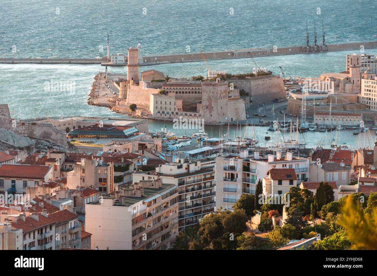 Marseille, Frankreich - 23. Juli 2010: Sonnenuntergang auf Notre-Dame de la Garde mit den lebhaften Straßen und dem alten Hafen darunter. Stockfoto